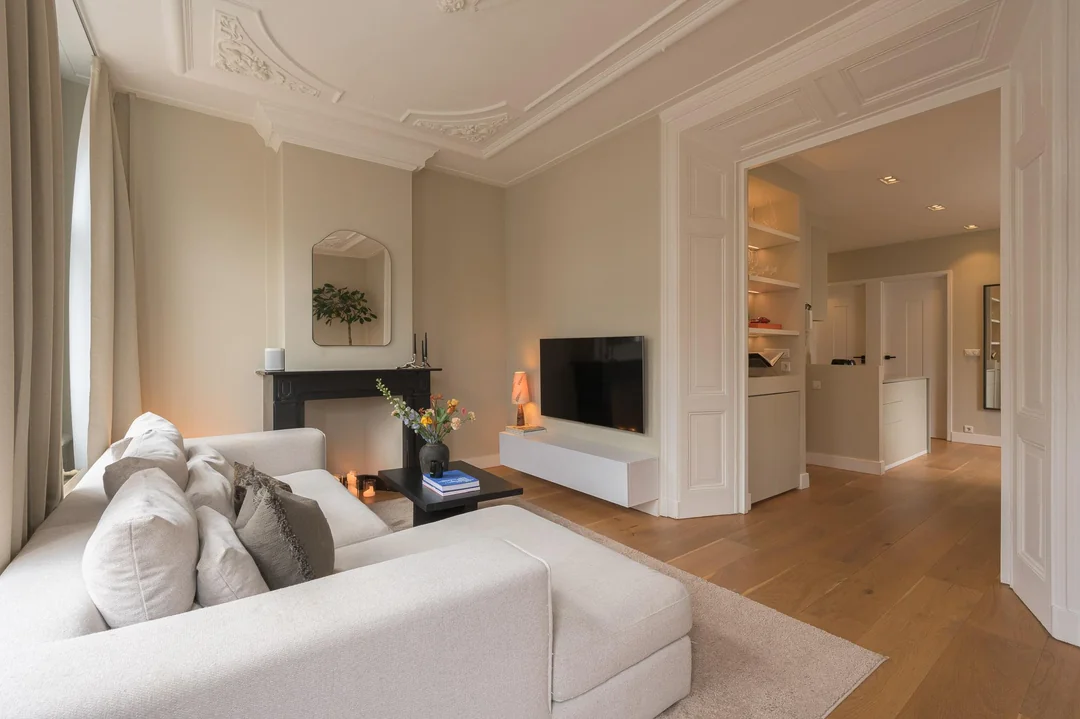 Classic apartment living room with ornate ceiling details and soft neutral furniture